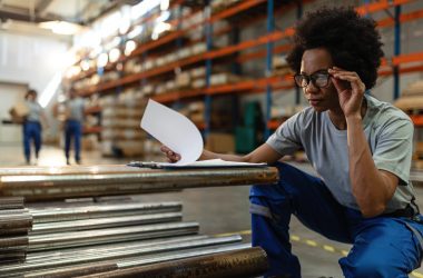 african american woman going through paperwork while working warehouse (1) african american woman going through paperwork while working warehouse (1)